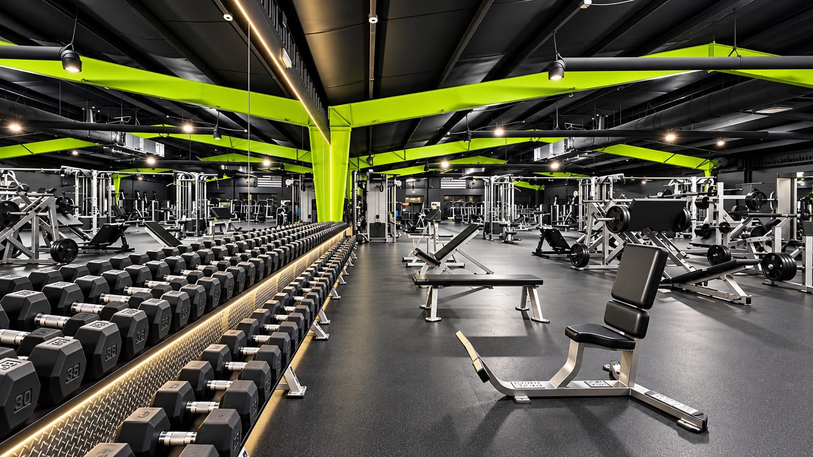 Dumbbell rack and benches under accent lighting at TNU Fitness